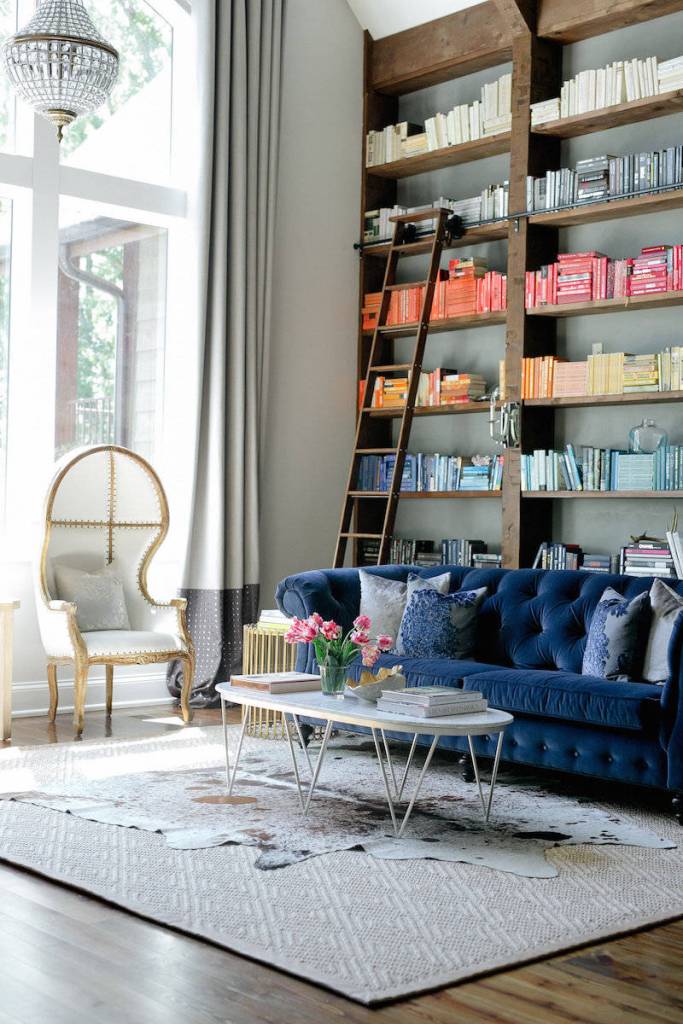 Blue velvet Chesterfield sofa near bookshelf