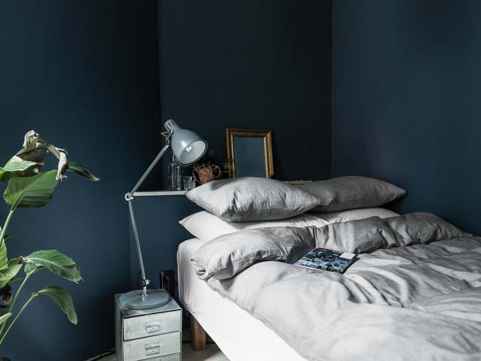 Light gray linen bedding dark blue bedroom wall