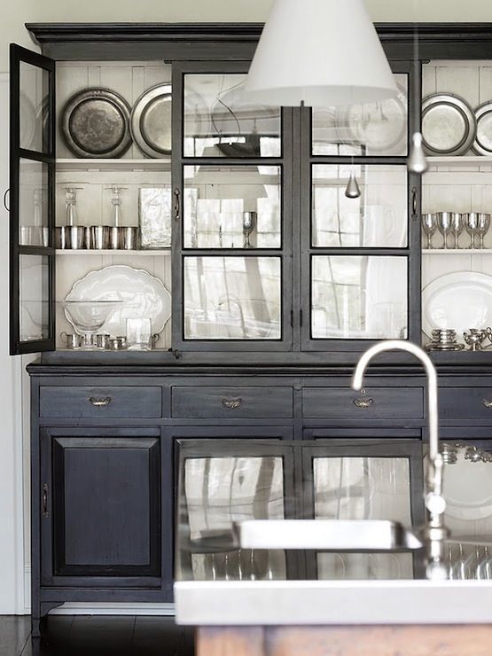 Painted black cabinetry with glass fronts backed with wide white .