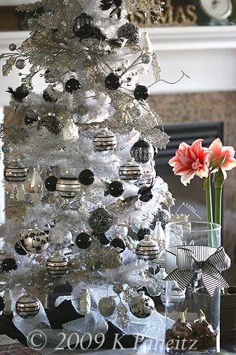 White flocked Christmas tree with black and silver ornaments .