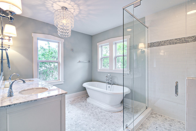 Spa-like master bath with glass chandelier and pedestal tub .