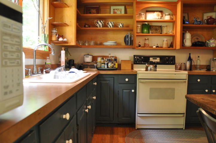 Two tone kitchen - dark blue base cabinets and natural wood uppers .