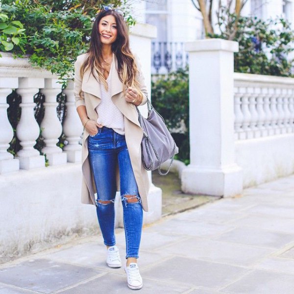 beige trench coat with ripped blue jeans and sneakers