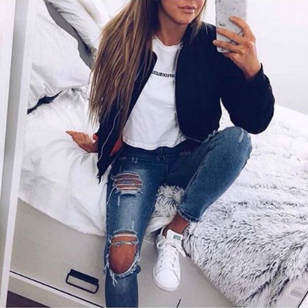 black bomber jacket with white graphic t-shirt and really torn blue jeans