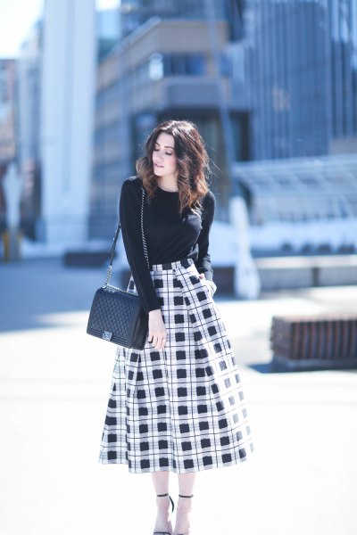 black sweater with round neckline and high-waisted, checked midi skirt