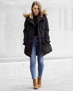 black bomber jacket with hood made of faux fur and slim-fitting ankle blue jeans