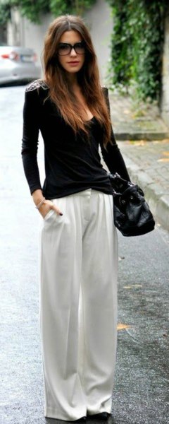 black figure-hugging sweater with scoop neckline and white pants