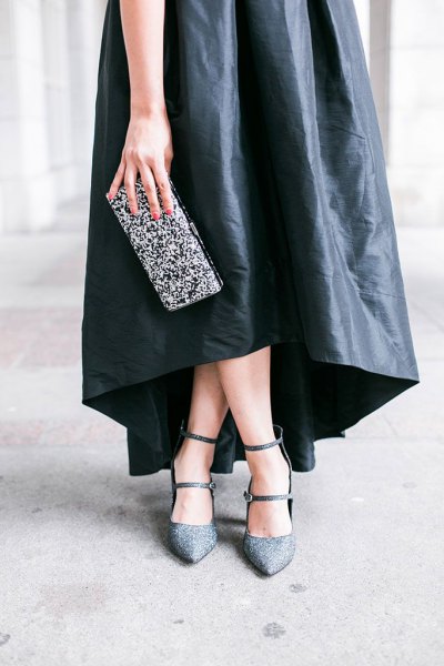 black maxi dress made of leather with a silver clutch made of sequins