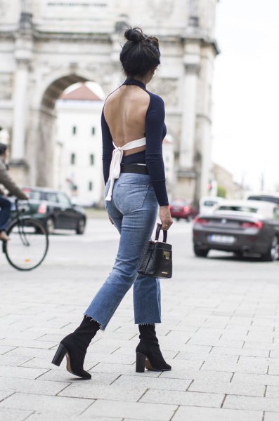 black backless long-sleeved top with blue, narrow-cut ankle jeans