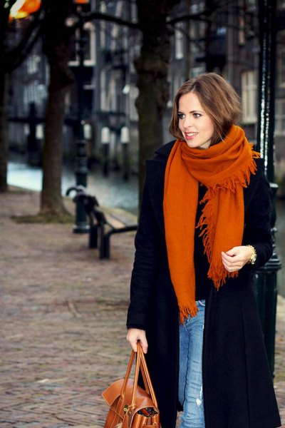 black long wool coat with blue skinny jeans and an orange knitted scarf