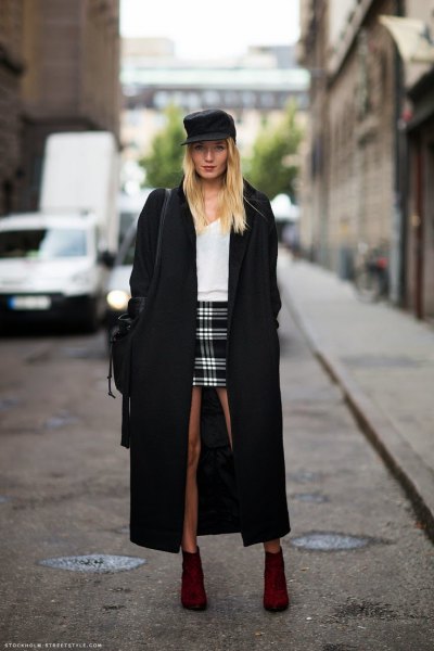 black maxi coat with white sweater and checked mini skirt