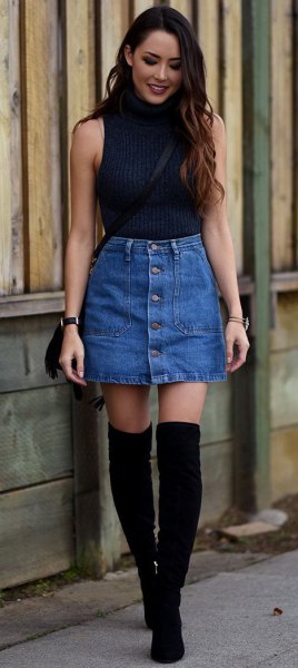 Black sleeveless sweater with stand-up collar and blue mini skirt with button placket on the front