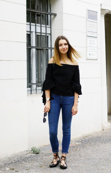 black off-the-shoulder blouse with half sleeves and blue skinny jeans