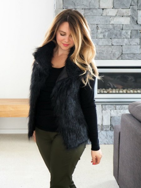 Black long-sleeved t-shirt with a scoop neckline, fur vest and gray slim fit jeans