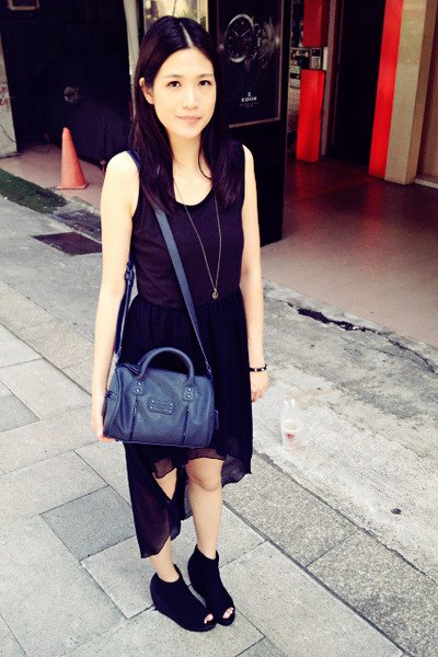 black sleeveless dress with high chiffon and scoop neckline and dark blue handbag