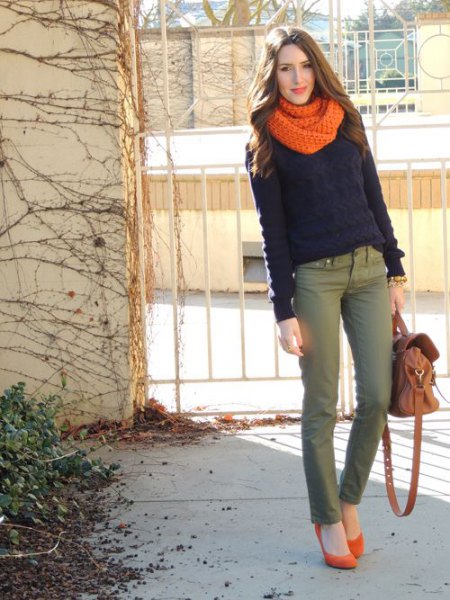 black sweater with an orange knitted scarf and gray chinos