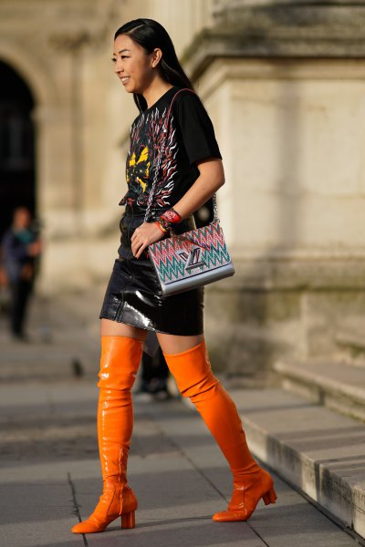 black t-shirt and leather skirt with overknee boots made of orange leather
