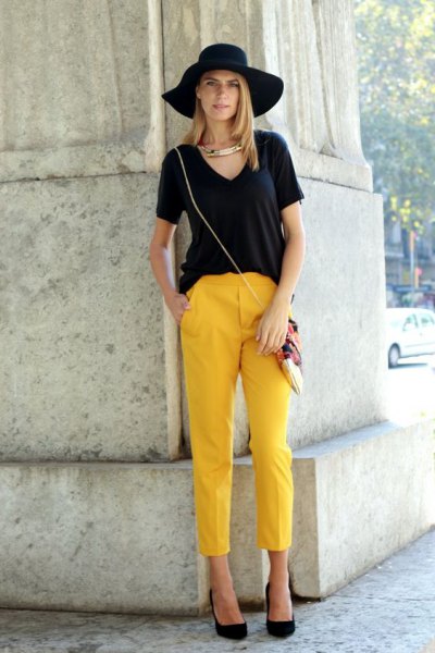 black V-neck T-shirt, floppy hat and cropped yellow pants
