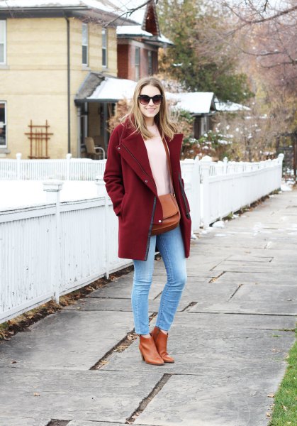 Burgundy-colored coat with an ivory-colored knitted sweater and light blue skinny jeans