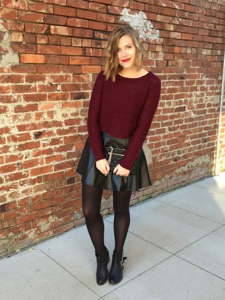 Burgundy-red, figure-hugging knitted sweater with black leather mini skirt and brown stockings