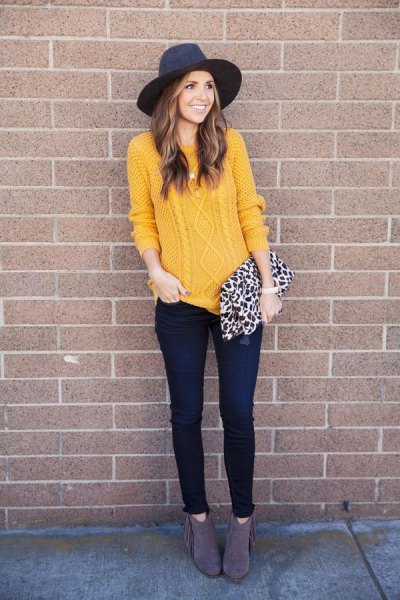 Cable knit mustard sweater with a black felt hat and wallet with a leopard print