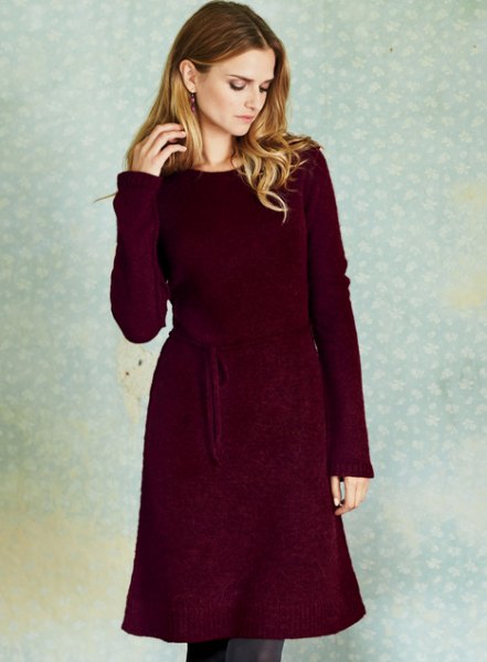 deep red long-sleeved sweater dress with belt and skinny jeans