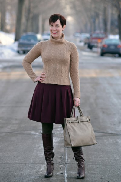 Figure-hugging green turtleneck with a black pleated skirt and brown tights