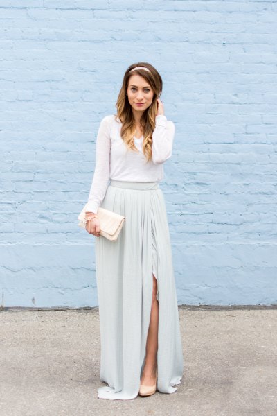 Long-sleeved floor-length dress with a gathered waist and a white clutch