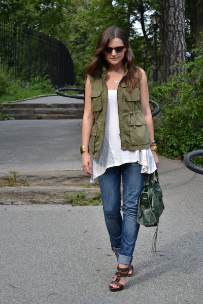 green utility vest with white sleeveless tunic top and blue jeans with cuffs