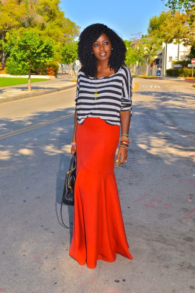 gray-black striped long-sleeved top with boat neckline and orange maxi skirt