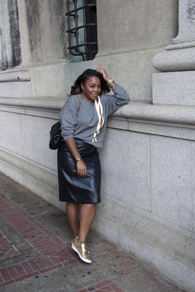 gray, chunky sweater with leather skirt and white and gold sneakers