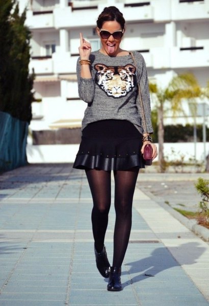 gray graphic sweater with black, flared miniskirt and short boots
