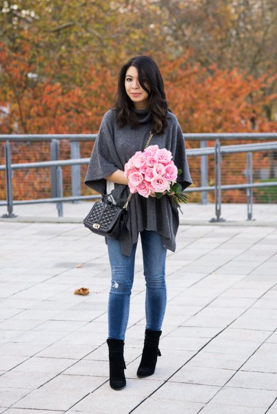 gray poncho sweater with blue skinny jeans and black boots