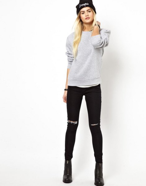 gray sweatshirt with ripped black skinny jeans and knitted hat