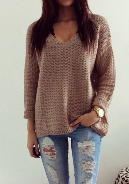 gray knitted sweater with a relaxed fit and V-neckline and torn boyfriend jeans