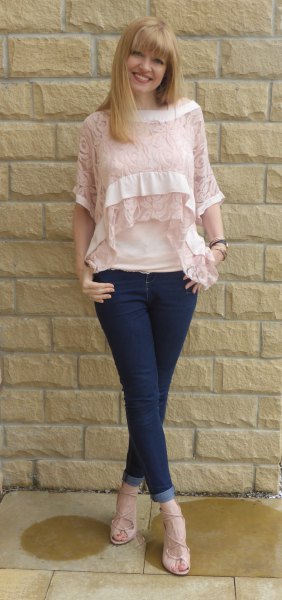 Blush blouse with half-sleeved lace neckline and dark blue skinny jeans with cuffs