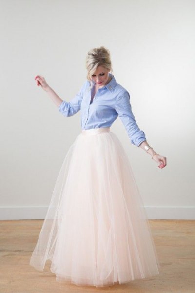 Light blue shirt with buttons and white, floor-length, flowing skirt with a high waist