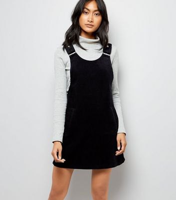 light gray mock neck sweater with black suspender dress