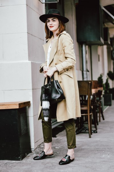 long beige trench coat with green trousers and felt hat