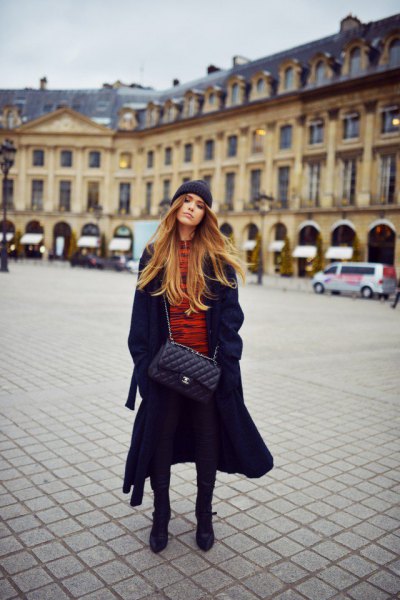 long black coat with an orange sweater and knitted hat