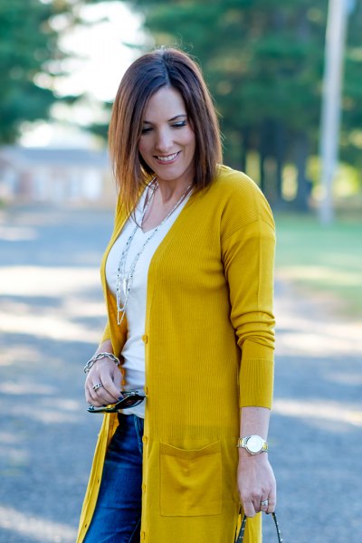 Mustard yellow knitted sweater with a white t-shirt with a scoop neck and blue jeans