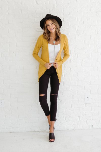 mustard-yellow cardigan with a black felt hat and ripped jeans