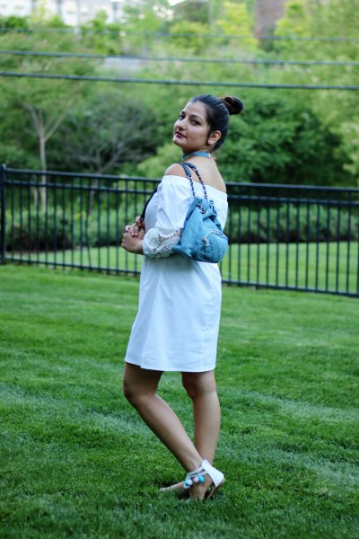Off-the-shoulder white mini blouse dress with light blue jeans backpack