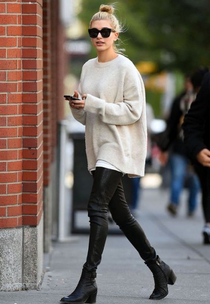 Cream-colored oversized knitted sweater with black leather gaiters