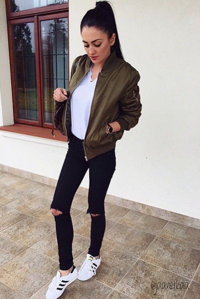 olive green bomber jacket with white blouse with V-neck and black jeans