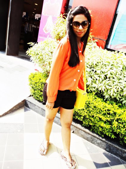 orange shirt with buttons and black mini shorts