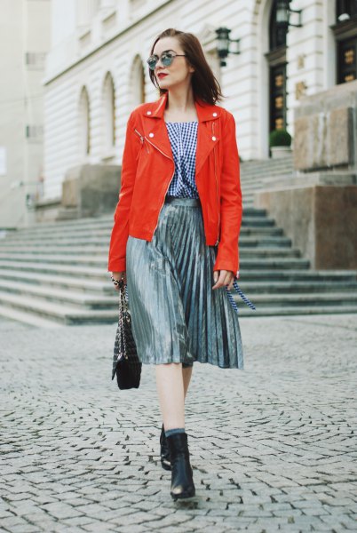 orange leather jacket with checked blouse and silver pleated skirt