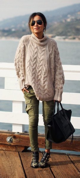 Light pink oversized cable knit sweater with green skinny cargo jeans