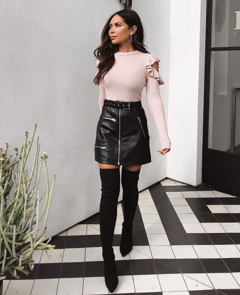 Light pink sweater with cold shoulder shape and black leather mini skirt with zip