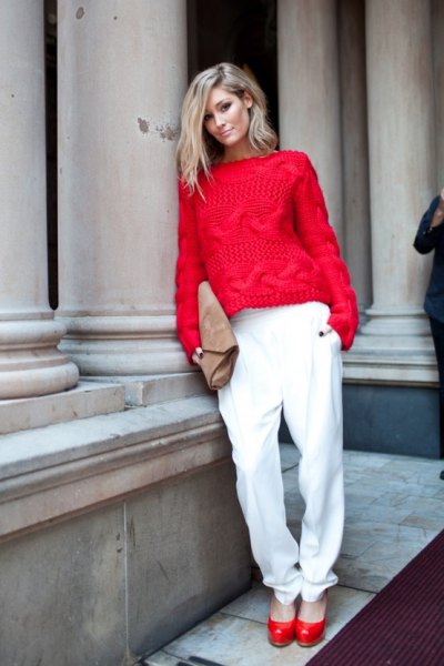 red cable knit sweater with white trousers with a relaxed fit